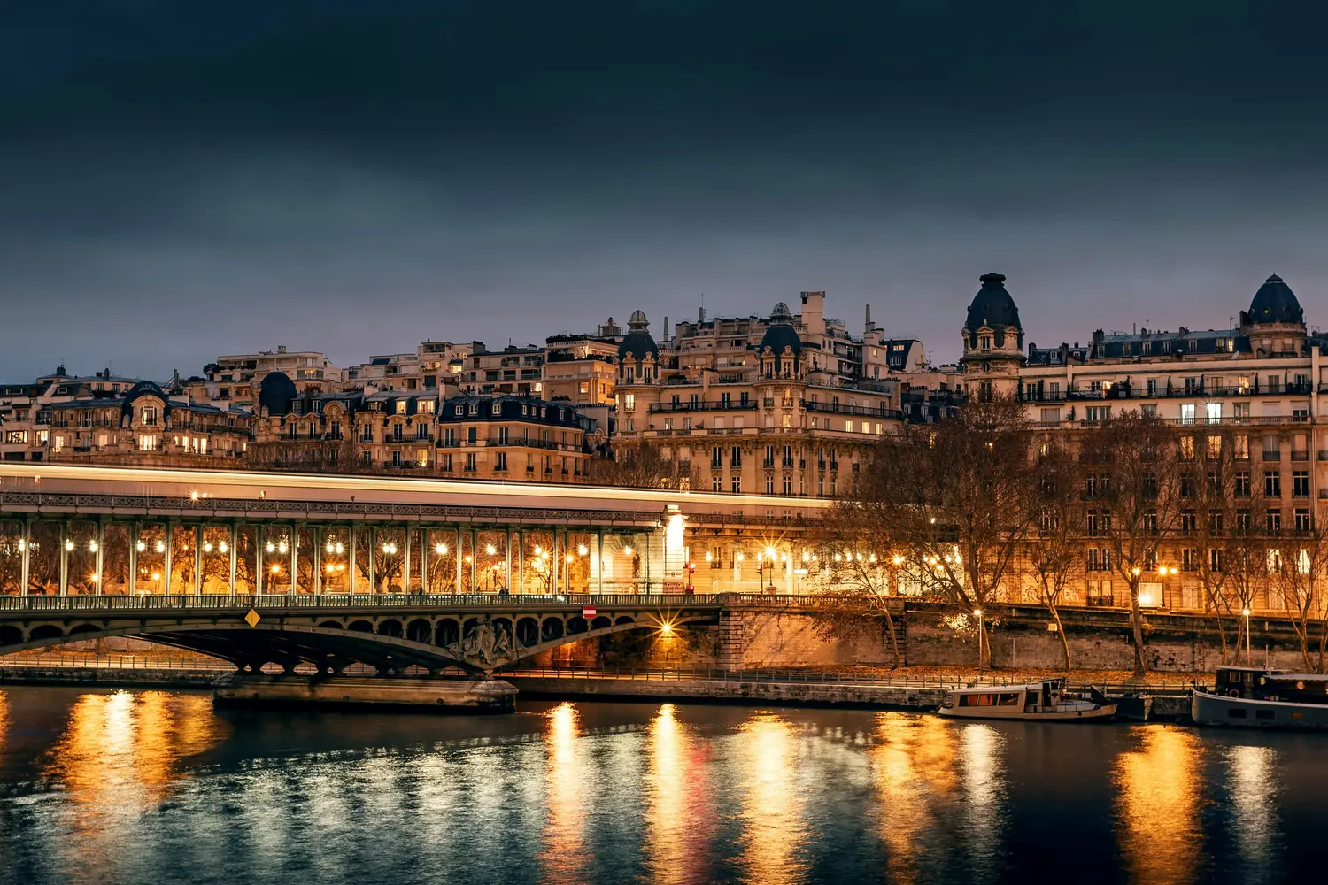 Illuminated Pont de Bir-Hakeim bridge crossing the Seine River at dusk in Paris, France