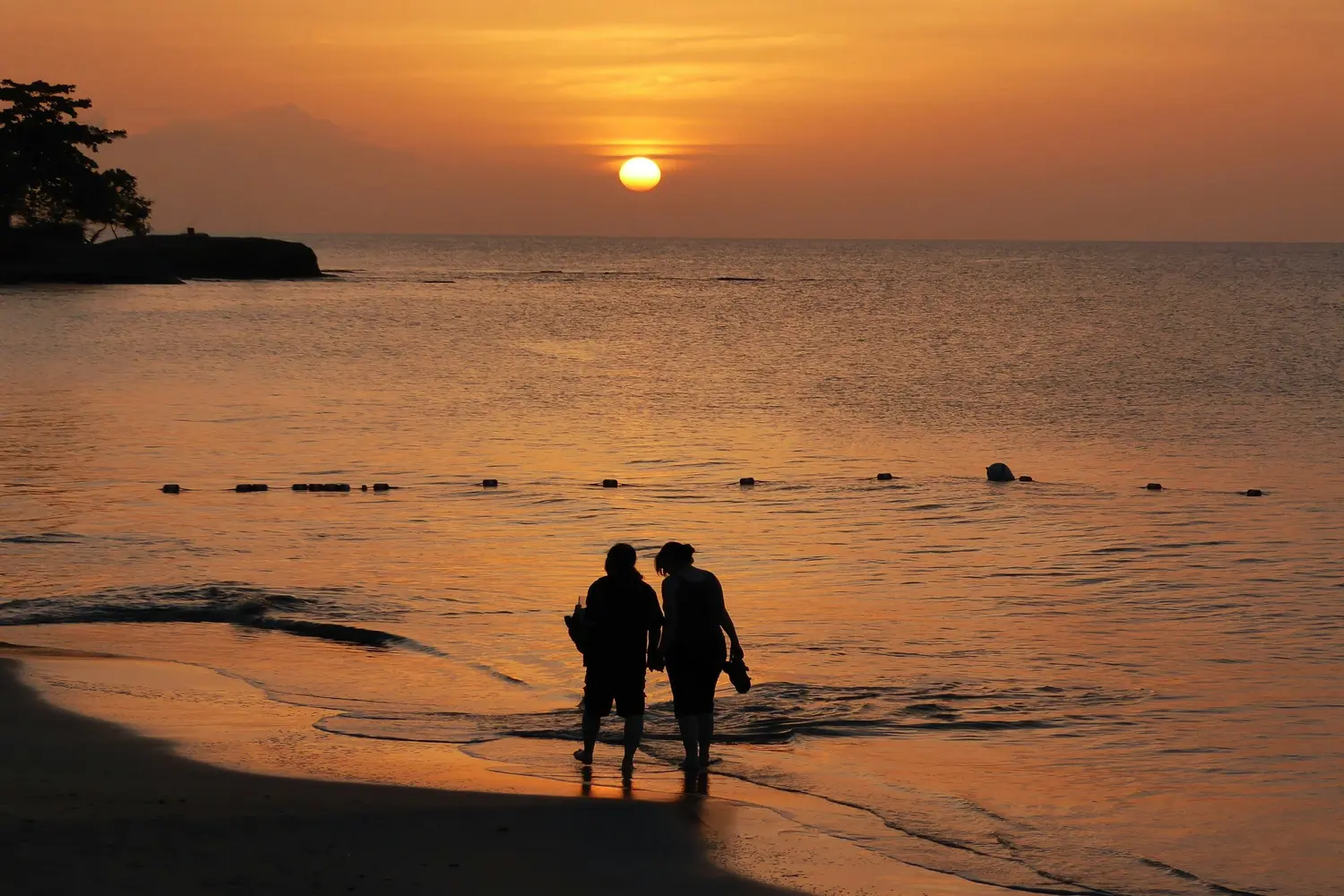 A couple walking on the golden sand at Halcyon Beach in Castries, Saint Lucia
