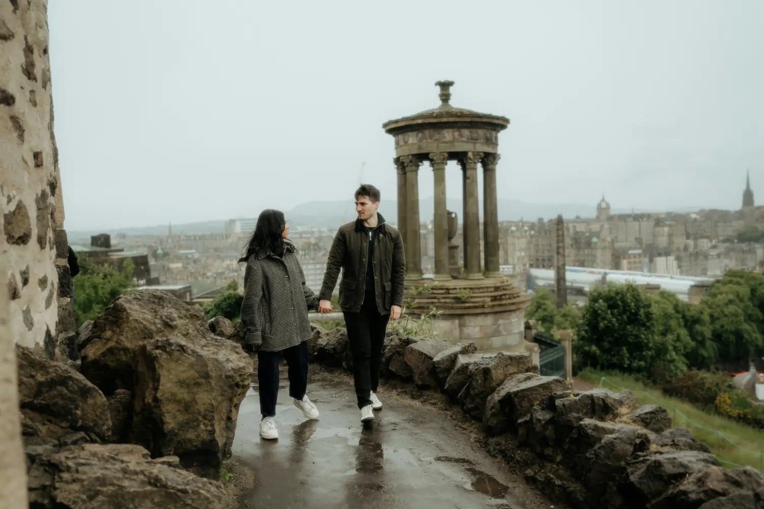 A couple walking near the Dugald Stewart Monument on Calton Hill in Edinburgh, Scotland