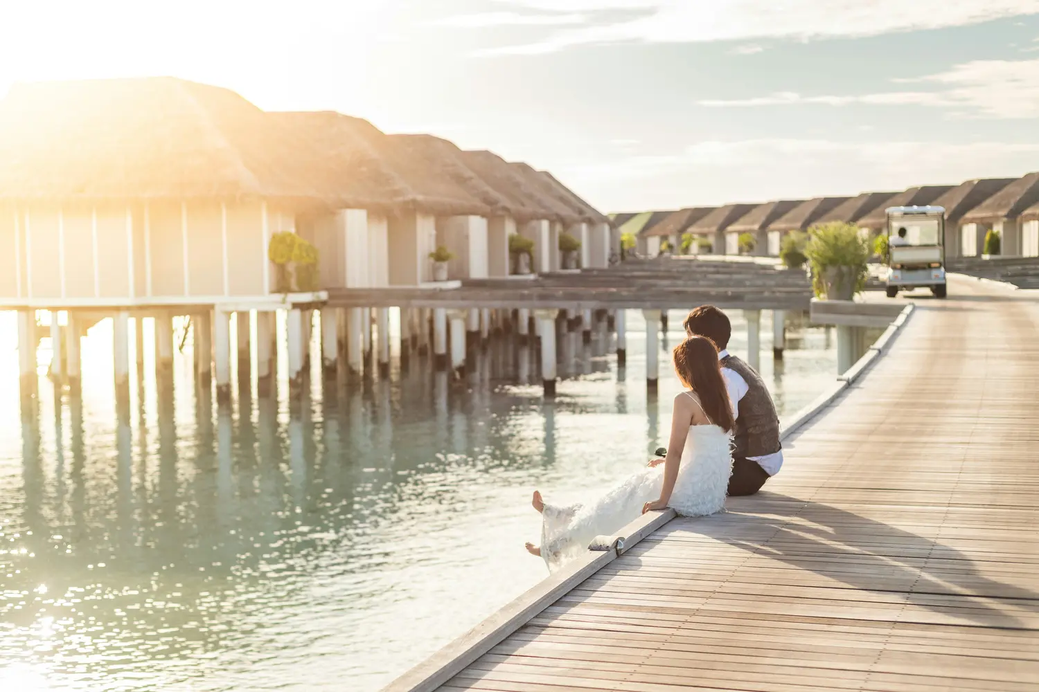 A couple sitting on the wooden overwater jetty of the resort in the Maldives.
