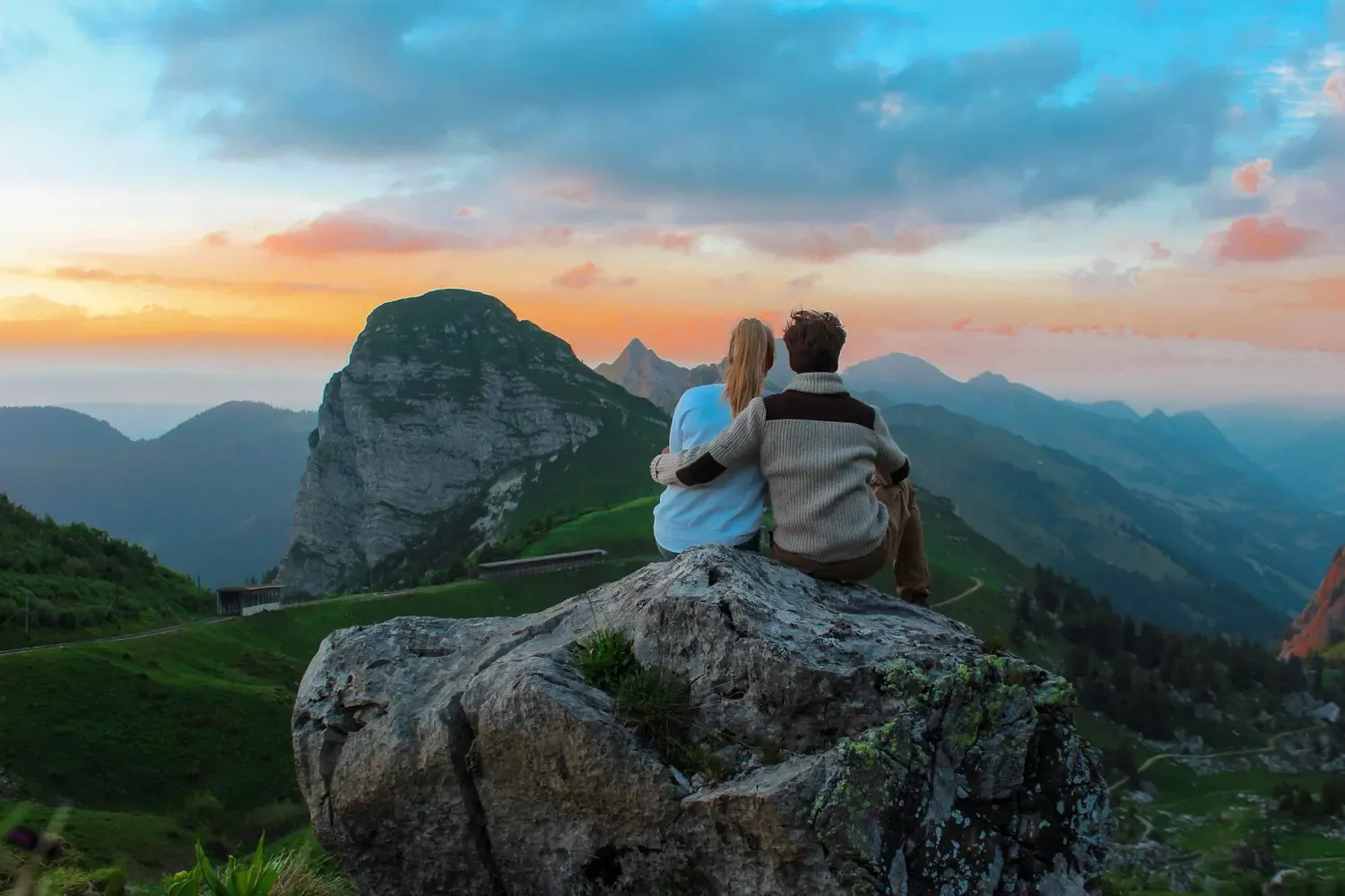 Couple sitting on rock facing mountain view