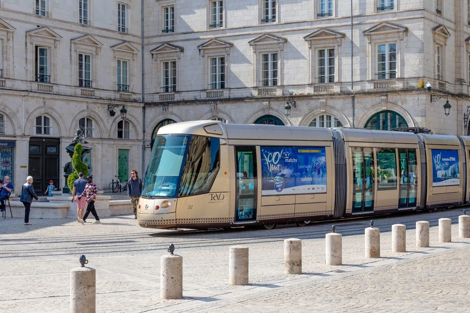 A modern tram travels through a historic square in Orléans, France