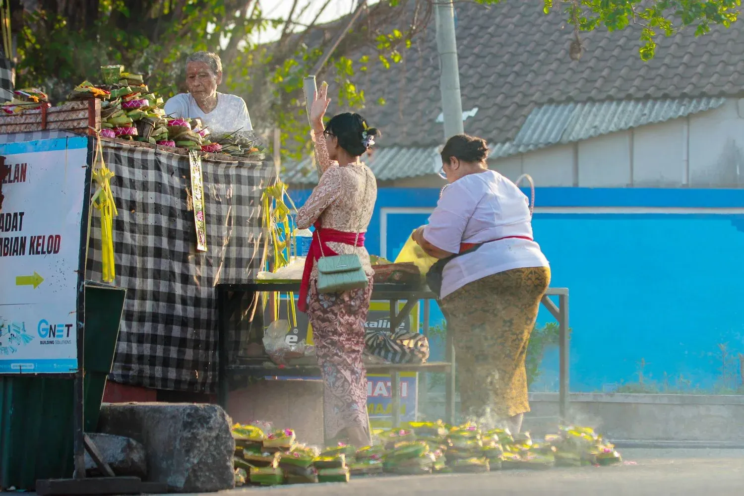 Balinese women in traditional attire preparing offerings at a Denpasar