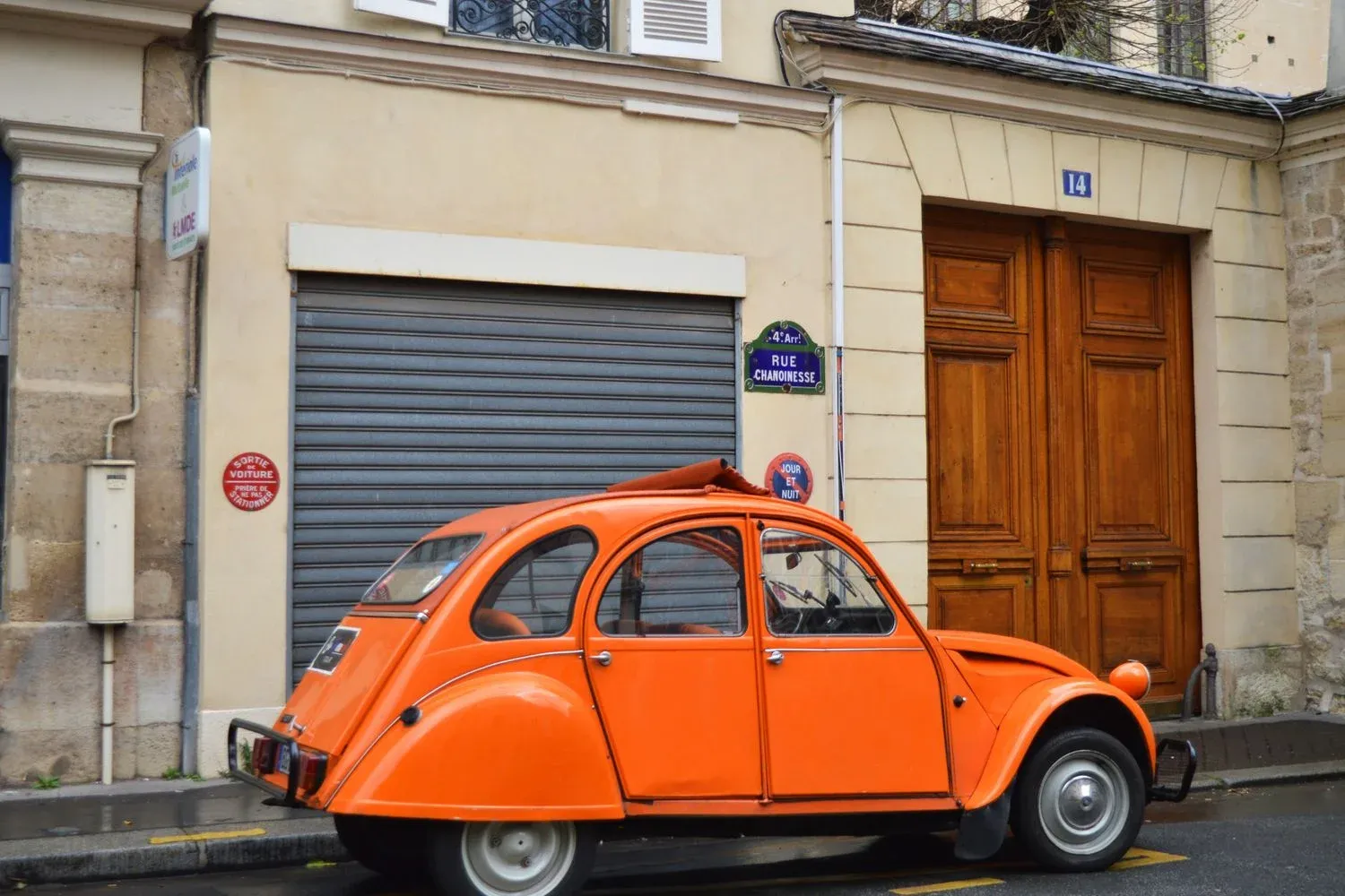 Classic orange car parked on Rue Chanoinesse in Paris