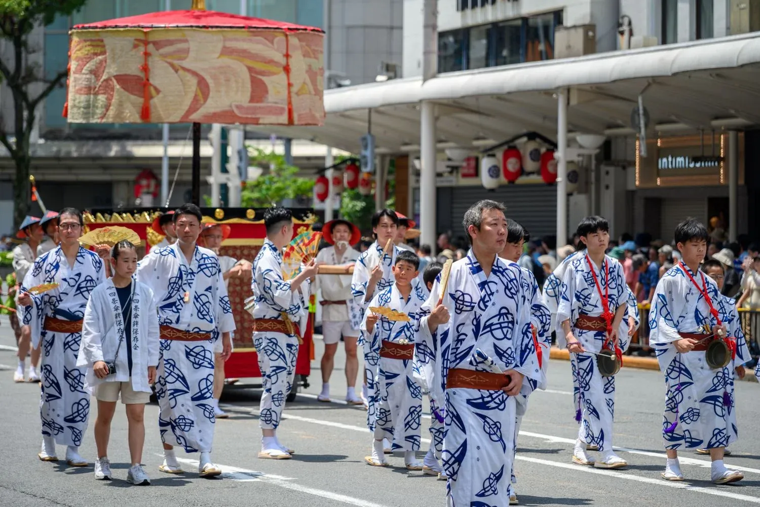 People in traditional attire parade through city streets during a Japanese festival