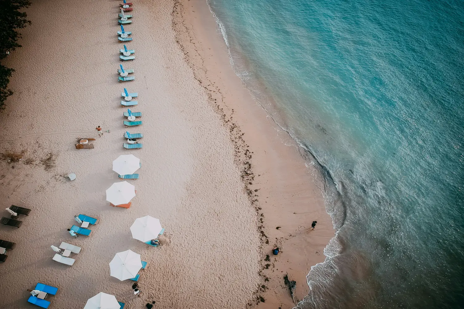 Sandy tropical coastline with rows of beach loungers, commonly associated with the eastern shore of Bali, Indonesia
