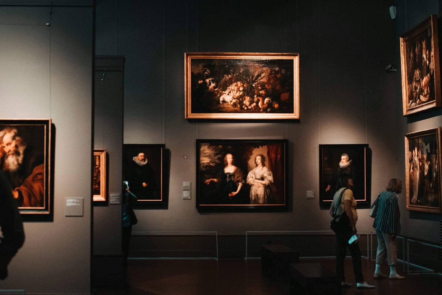 Gallery interior with framed classical oil paintings hanging on dark walls