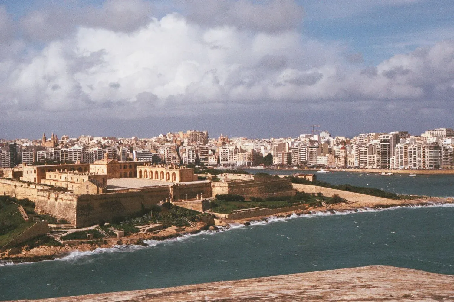 View of a historic fort and urban cityscape along Malta's coastline