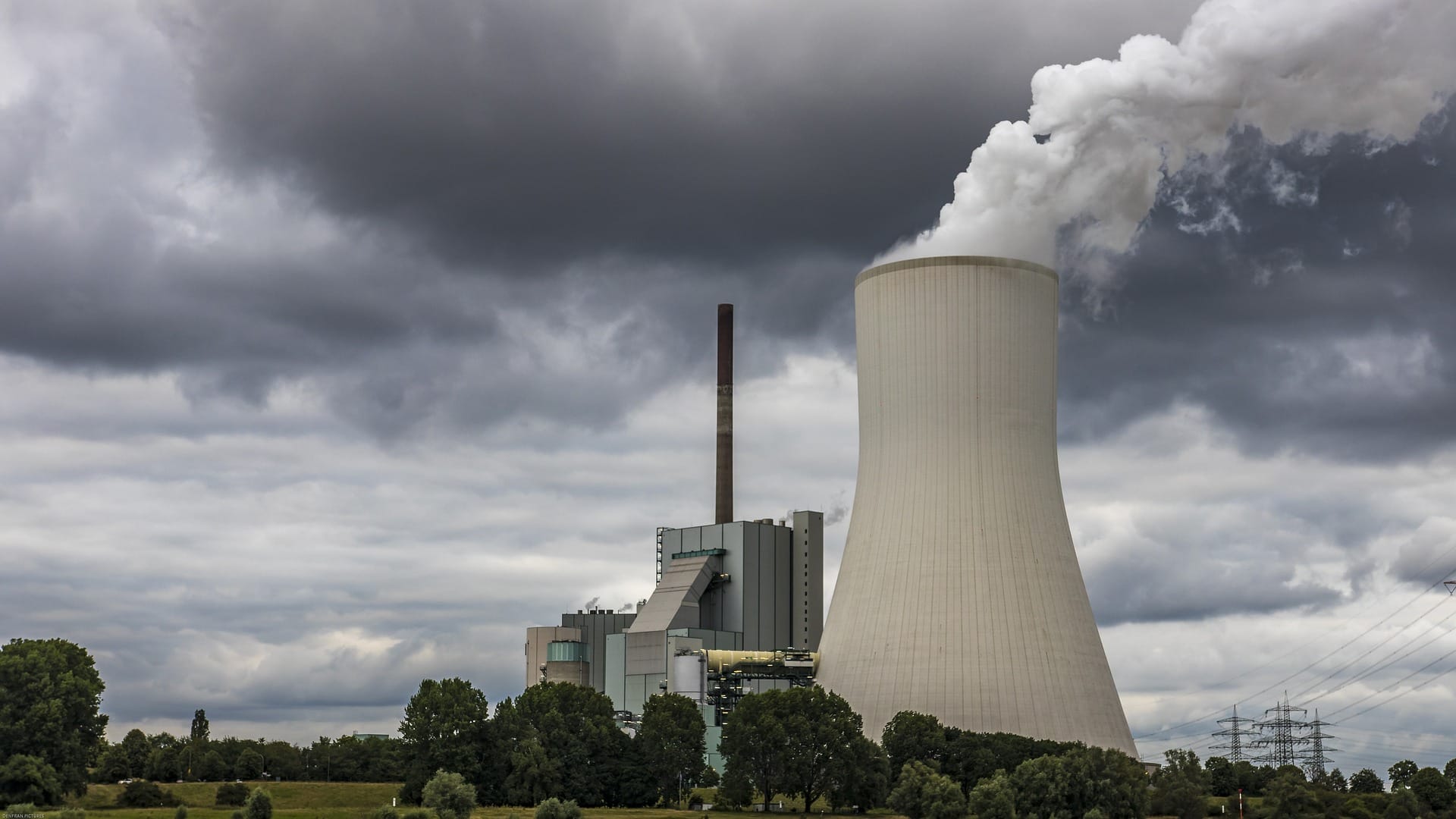 A large regional nuclear powerplant in a rural environment.  Cloudy overcast sky with green trees