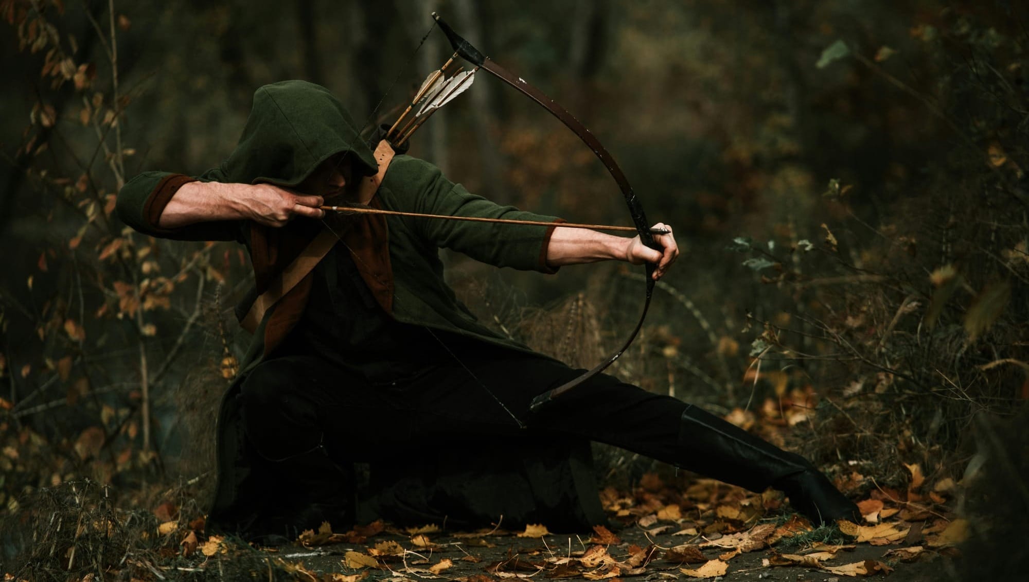 Archer in Green Hood Aiming in Forest