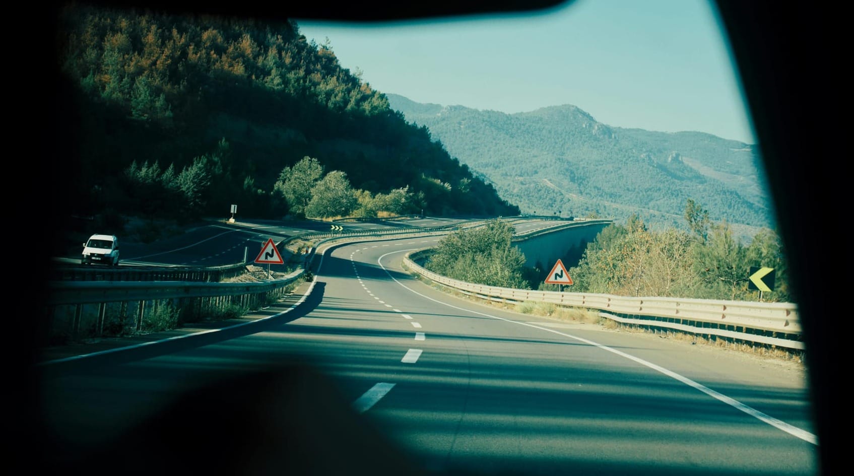 A scenic view of a winding highway passing through lush mountains
