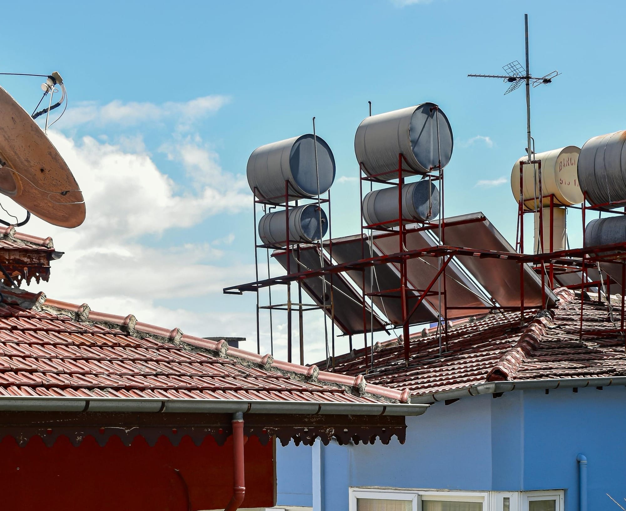 Colorful rooftops with solar water heaters in sunny urban setting.