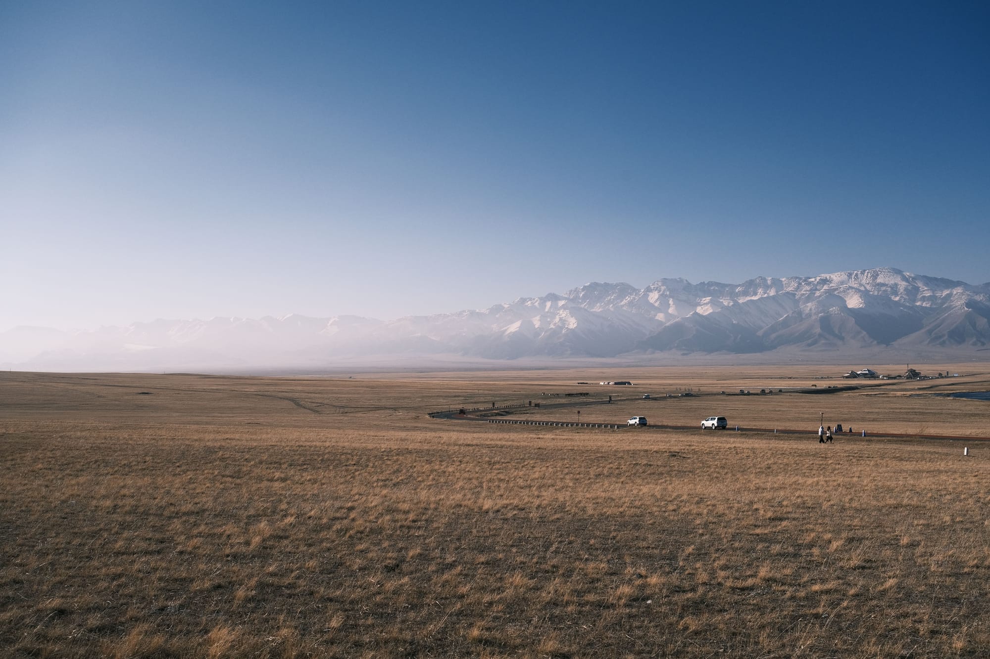 Wide view of vast plains and distant mountains under a bright blue sky. by 易 凡