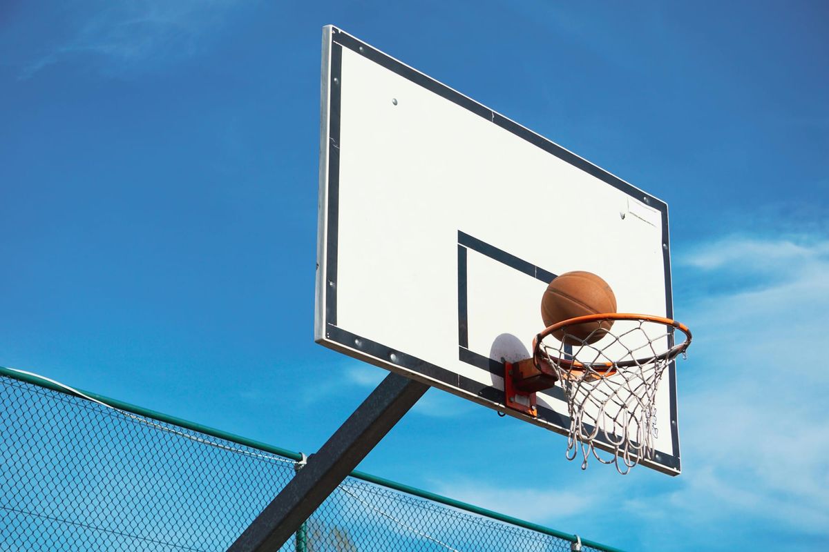 Basketball Entering a Net, clear blue sky background.