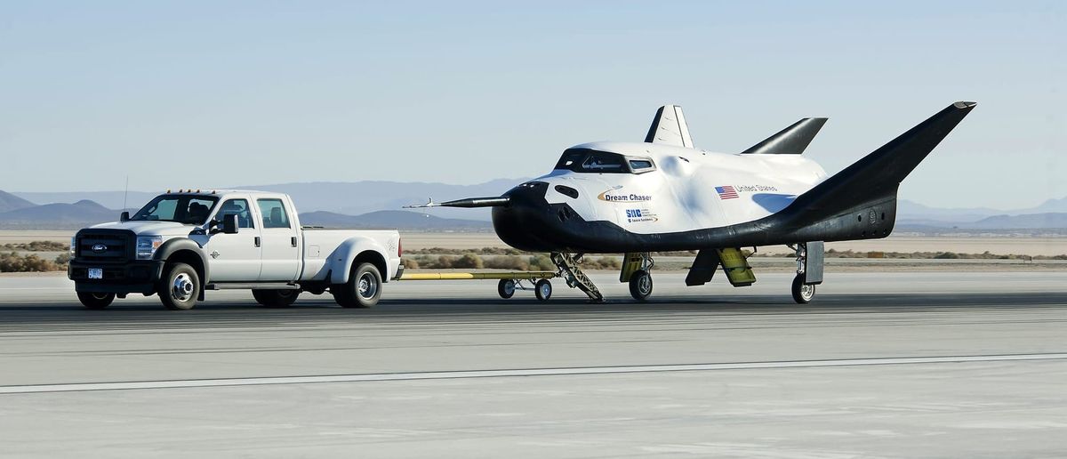 Dream Chaser being driven along the runway by a pickup truck after an atmospheric test