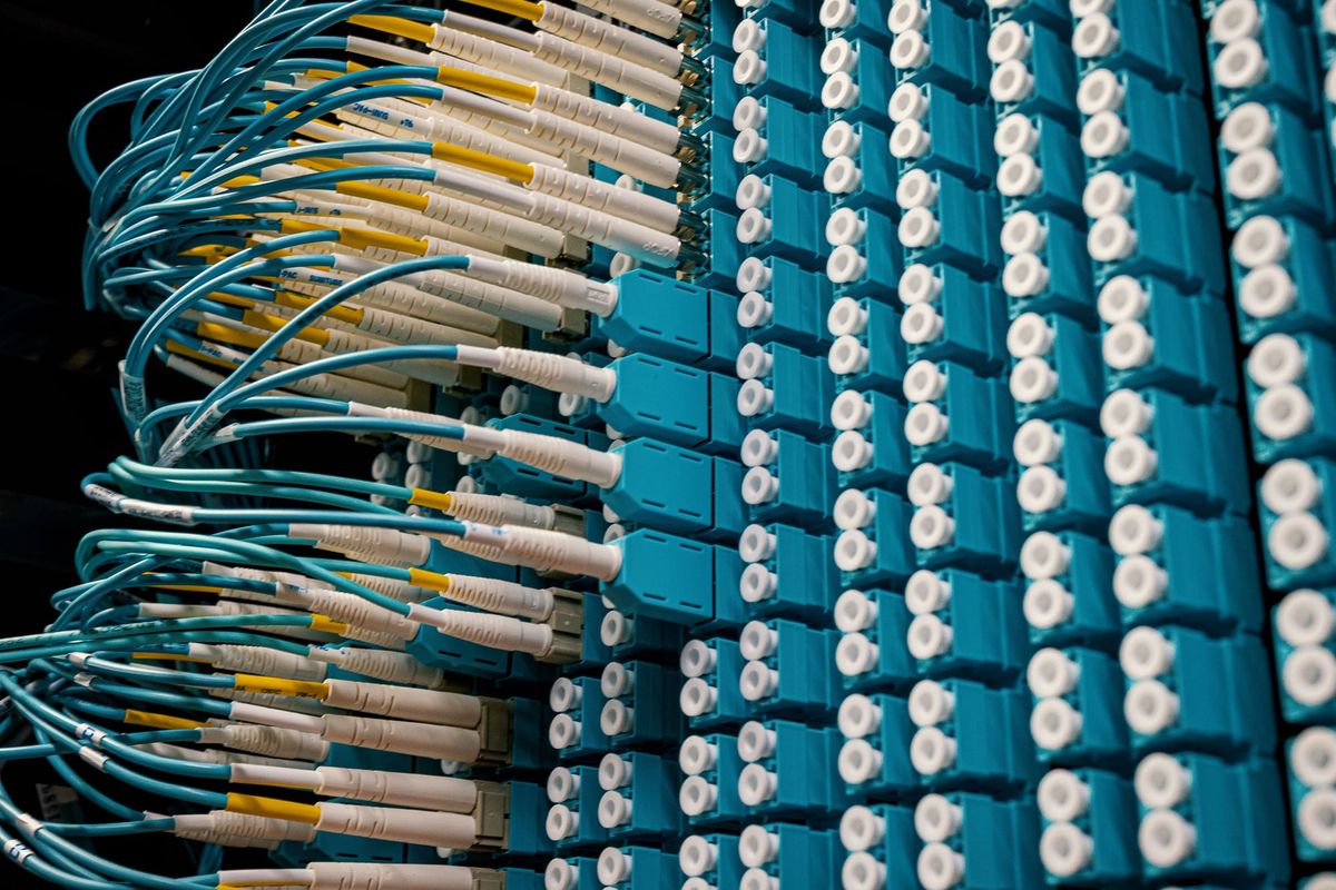 Detailed view of fiber optic cables connected in a data center rack, showcasing modern networking technology.