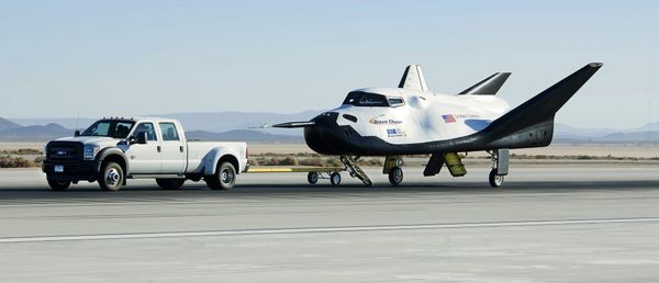 Dream Chaser being driven along the runway by a pickup truck after an atmospheric test