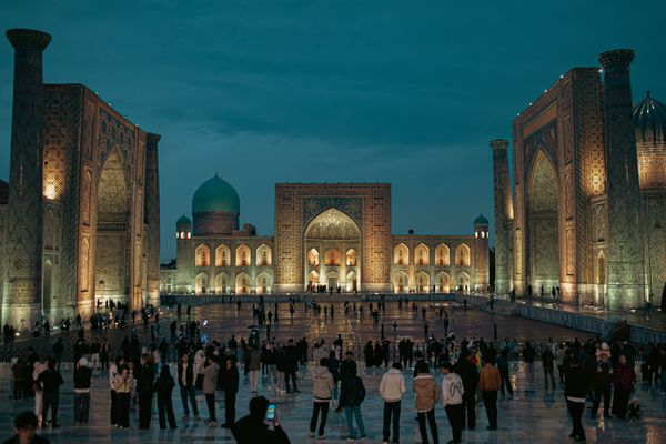 Crowds gather at dusk in the historic Registan Square, Samarkand's iconic Islamic architecture site.