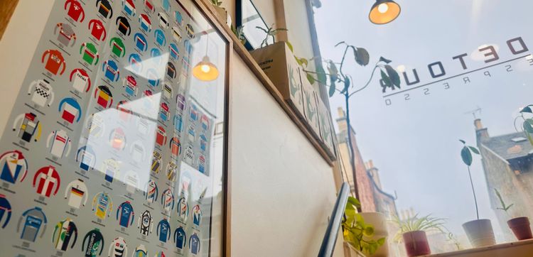 View with a poster of illustrated cycling tops in the foreground, looking out of a cafe window.