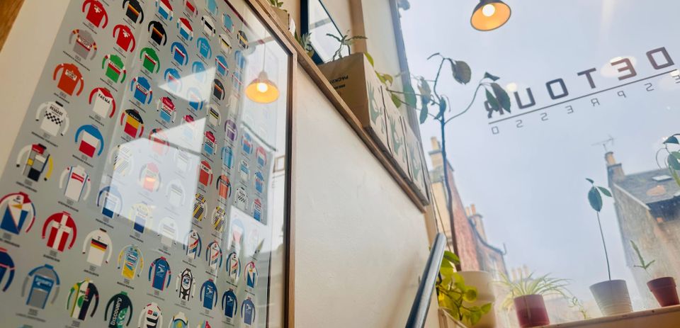 View with a poster of illustrated cycling tops in the foreground, looking out of a cafe window.