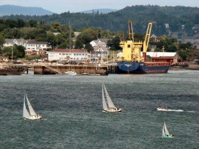 A BUSY HARBOR ON A SUMMER'S DAY. Racing to the finish line, Passamaquoddy Yacht Club members sail by Eastport and the Clipper Meridian, docked at the breakwater, during the Roosevelt Cup Cha