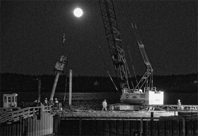 THE FULL “SNOW” MOON RISES behind the workers from CPM Constructors rebuilding the Eastport breakwater on February 22. (Edward French photo)
