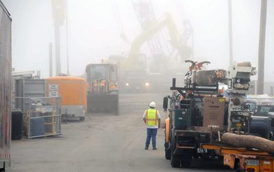 A FOGGY BALLET. Heavy construction equipment moves through the mist as CPM Constructors drives sheet piling and removes fill from the Eastport breakwater on an August morning. The reconstruc
