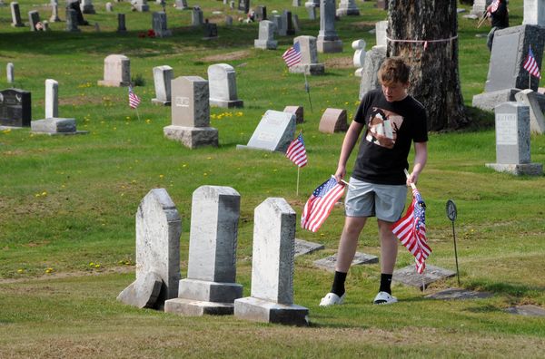 HONORING THEIR SACRIFICES. Placing flags at the graves of veterans in Hillside Cemetery in Eastport on May 19 in preparation for Memorial Day were Shead High School U.S. history and governme