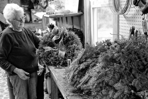 'TIS THE SEASON. Looking over a decorated Christmas wreath she just made from princess pine tips is Kathy Bishop of Bishop Tree Farm in Perry. The Bishop family has a long tradition of makin