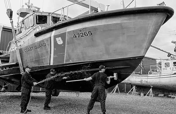 A CLEAN SWEEP. Scrubbing the bottom of the U.S. Coast Guard's 47-foot motor lifeboat at Deep Cove Marine Services are coastguardsmen from Station Eastport. The boat was hauled out for an eng