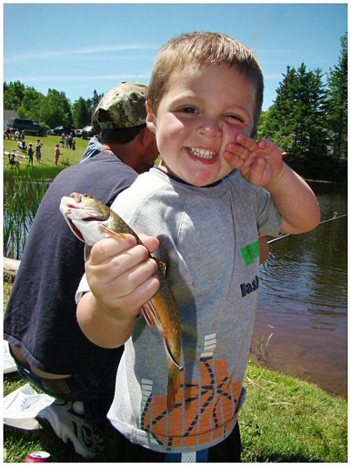 CATCH OF THE DAY. Brayden Flood, 3, of Edmunds proudly displays his first trout, caught at the 11th annual Moosehorn National WIldlife Refuge Children's Fishing Derby. (Chessie Johnson photo