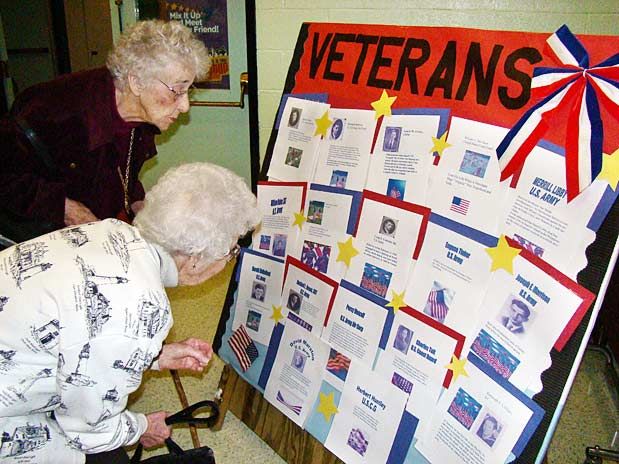IN REMEMBRANCE, Ruth Dean, 90, and Edith Comstock, 91, look over a display commemorating Lubec veterans that was created by Lubec High School students who used photographs and information su