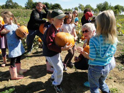 A FUTURE JACK-O-LANTERN? Struggling with his hefty prize as teacher Pauline Cates prepares to mark his pumpkin at the Enest James farm in Charlotte is Whiting Village School first grader Kay