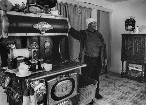 ONE OF MANY STRUGGLING with high fuel costs, Anna Baskerville stands in front of a wood burning stove that she is unable to use this winter in her Eastport home. The dining room entrance is 