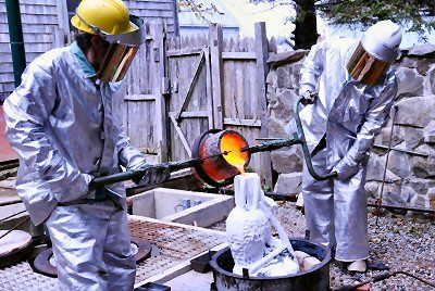 POURING molten bronze into the shell mold for a section of the mermaid sculpture to be placed on the Eastport seawall are Bill Labbadia (left) and Dick Klyver. The casting was carried out at