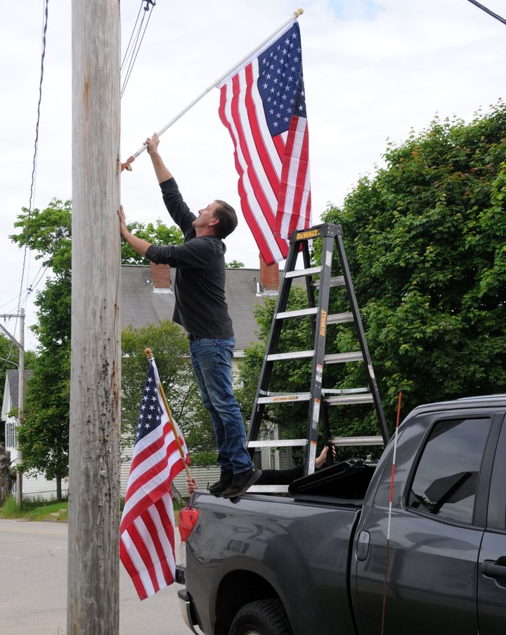 GETTING READY FOR THE FOURTH OF JULY, Donnie Peters of the Eastport city hall staff, assisted by Paige Atkinson, places U.S. flags on poles in the city at the start of the summer season. (Ed