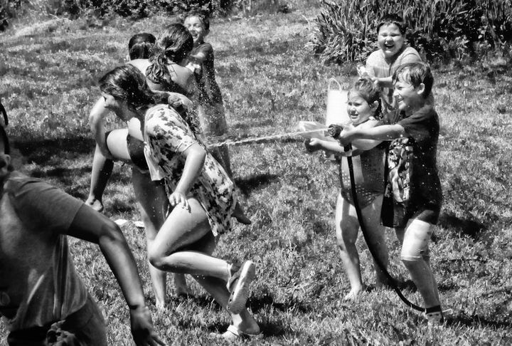 HAVING FUN IN THE SUN by spraying water on each other are these children at a birthday party in Eastport's North End earlier this month. (Edward French photo)