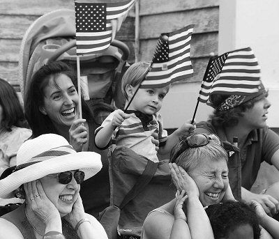Sirens from police, fire and ambulance vehicles in the parade cause some to cover their ears and others to wave their flags (middle).