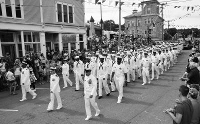 Sirens from police, fire and ambulance vehicles in the parade cause some to cover their ears and others to wave their flags (middle).