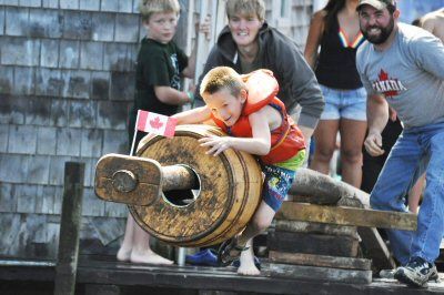Noah Leonard attempts to capture the flag at the end of the greasy pole during the Canada Day celebration on July 2 at Seal Cove creek on Grand Manan Island. ( Jennifer Pierce photo)