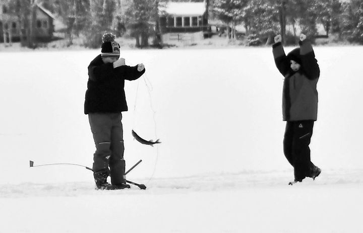 PULLING A PICKEREL out of an ice-fishing hole is Beau McLaughlin of Baileyville, as Oliver Bishop cheers him on during the Calais Lions Club's fishing derby on Round Pond on January 27. See 
