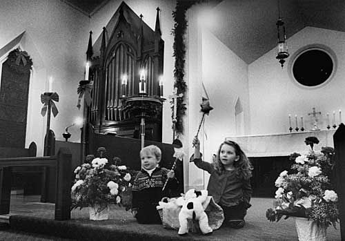 SURROUNDED BY LIGHT. "Away In A Manager" is sung by Roy Duffy, 3, and his four-year-old sister Siobhan as they raise their stars while kneeling by a manger during the Christmas Eve service a