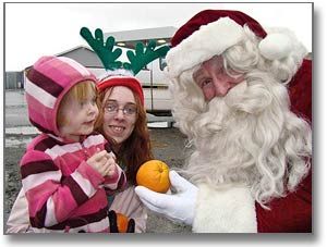 HO, HO, HO. Santa knows who's been naughty or nice this year, as he rewards Lauren Munson, 3, with an orange during the Santa Claus parade in Lubec on December 7. Santa is assisted by one of