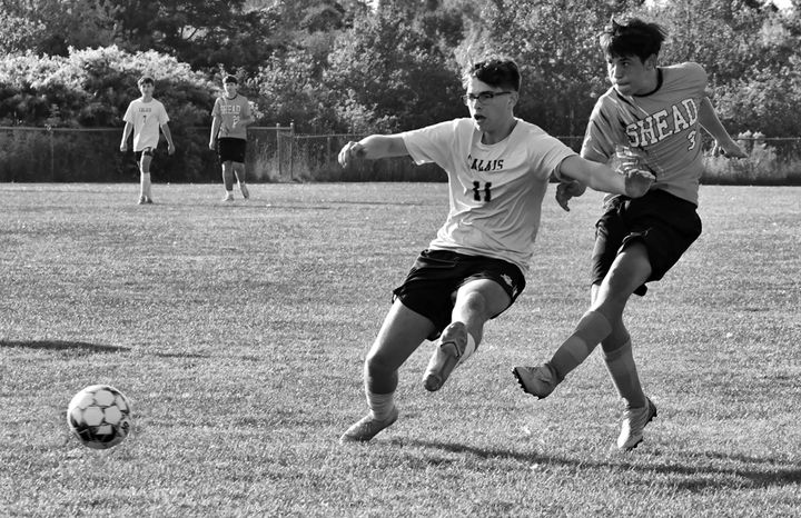 ELLIS SANCHEZ of the Shead Tigers takes a shot and scores a goal against Calais as Kaeson Dana defends during a high school soccer game on September 16. Calais won the game by a score of 2'1
