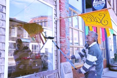 A FRESH, NEW LOOK. With the arrival of spring, Reggie Drew cleans the windows at Port O' Call in downtown Eastport, as businesses prepare for the upcoming summer season. (Edward French photo