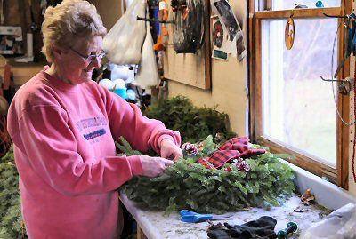 GETTING READY FOR THE HOLIDAYS. Decorating a wreath at her shop in Perry is Kathy Bishop. Boyden Lake Creative Products also sells kissing balls, swags, garlands, candy canes and cemetery ba
