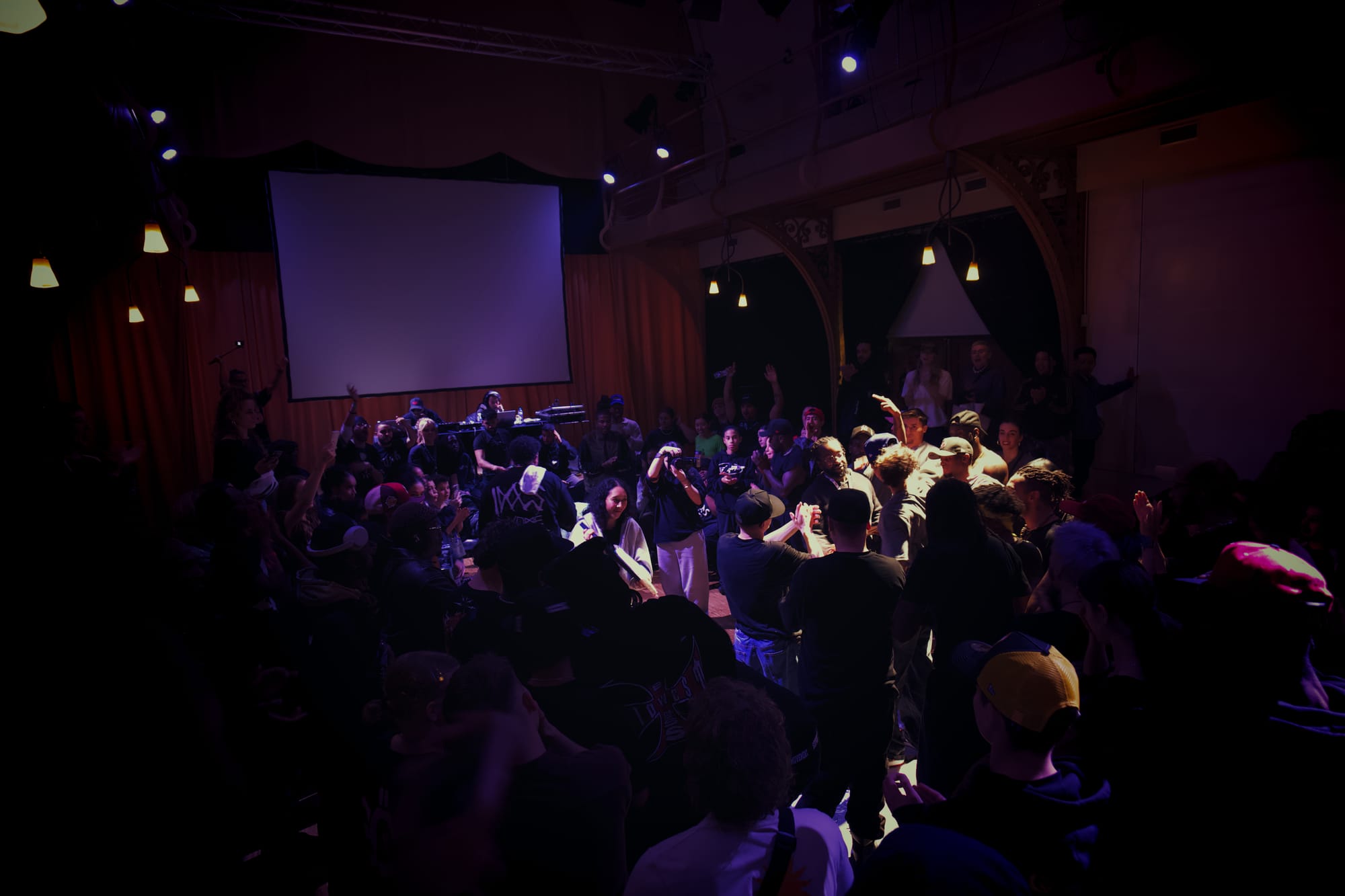 The audience is standing around the dancefloor while the judges are announcing the winners of the battles. They are also giving them their rewards.