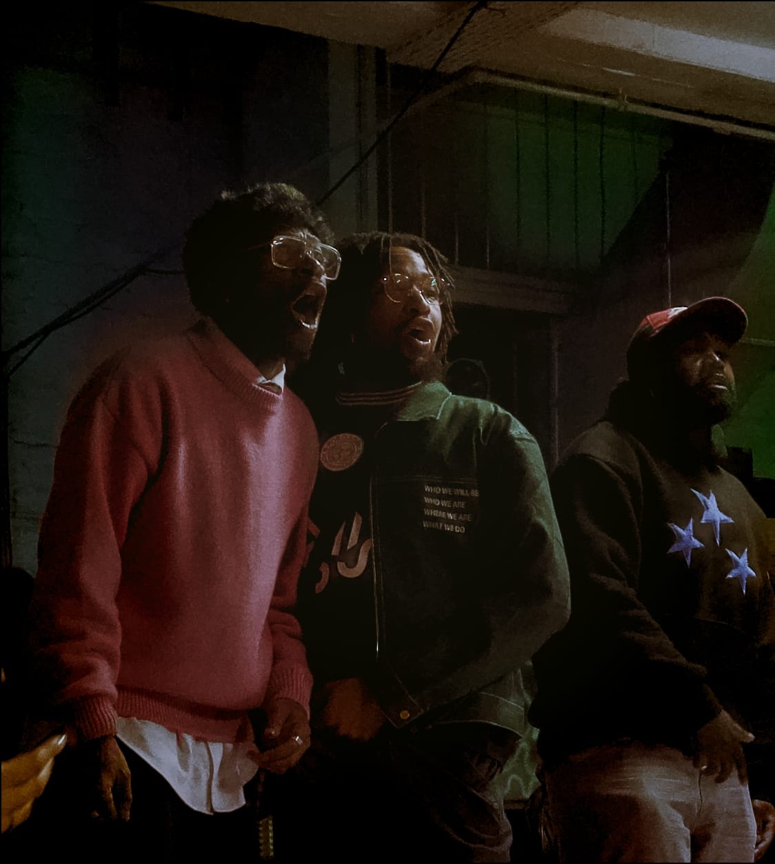 2 people from the audience looking at the battles. Both of them are wearing glasses. The person on the left is wearing a pink jumper and the person on the right is wearing a green jacket.