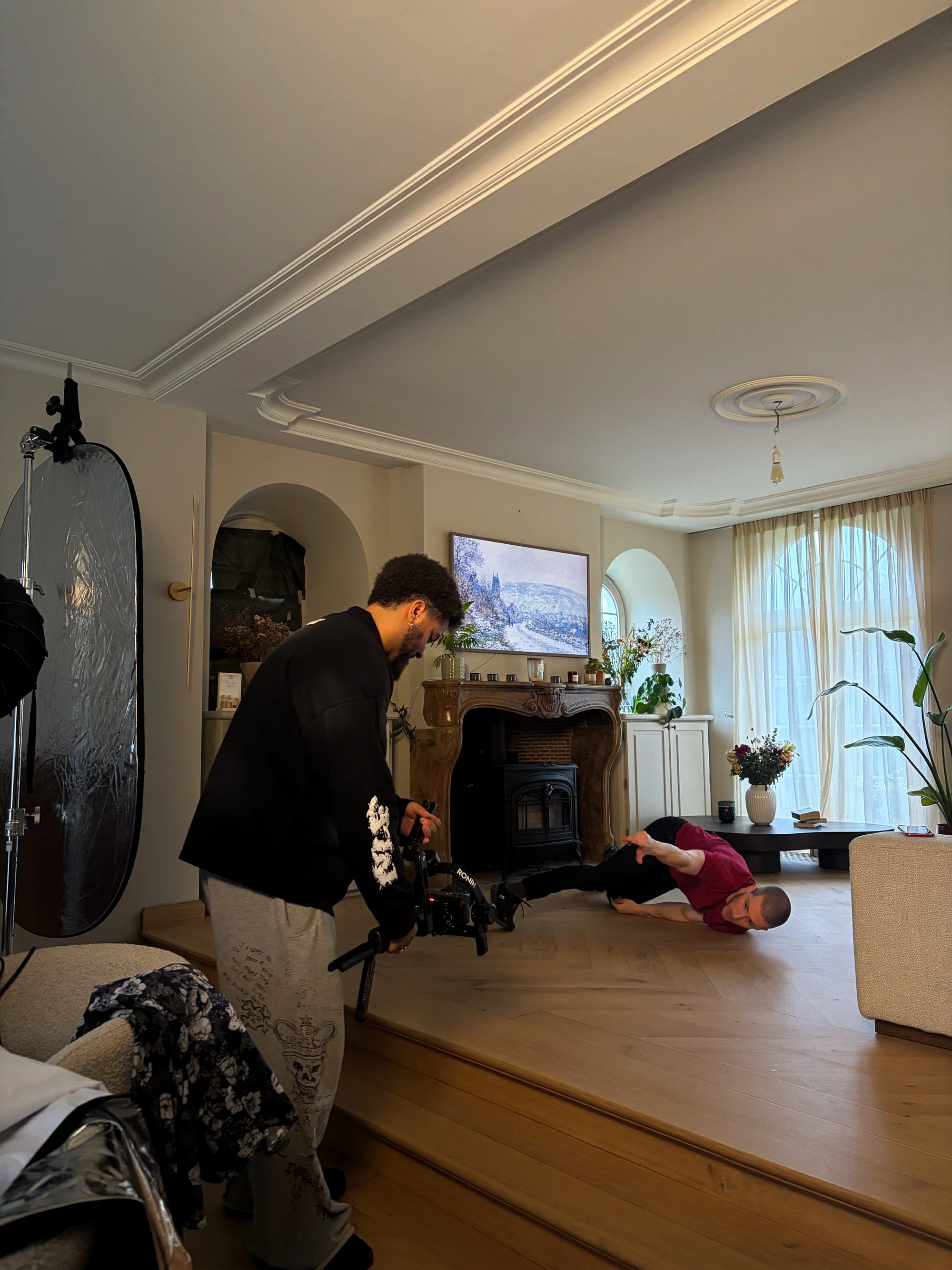 Adam is filming Slim B, who is dancing on the floor in the living room.