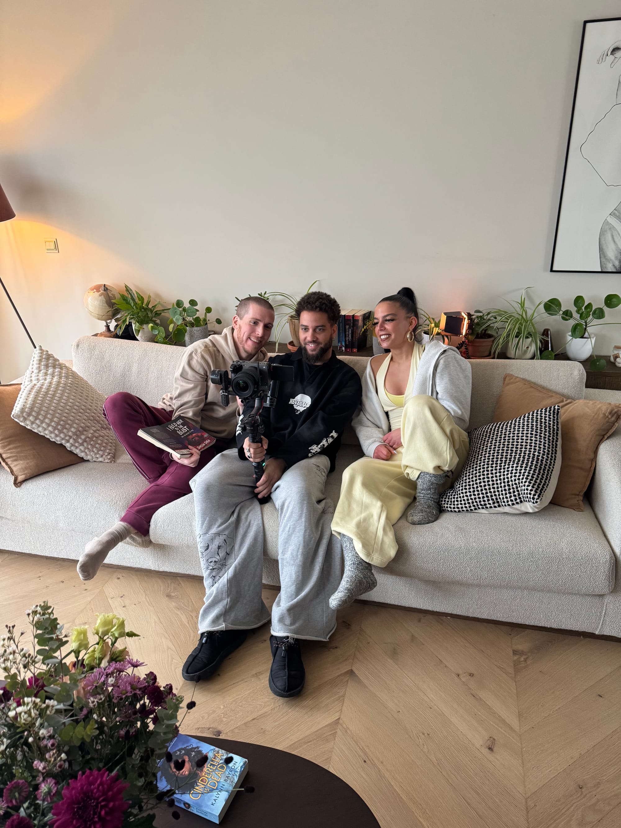 Slim B, Adam, and Pippa are sitting on the couch and watching a take on the camera.